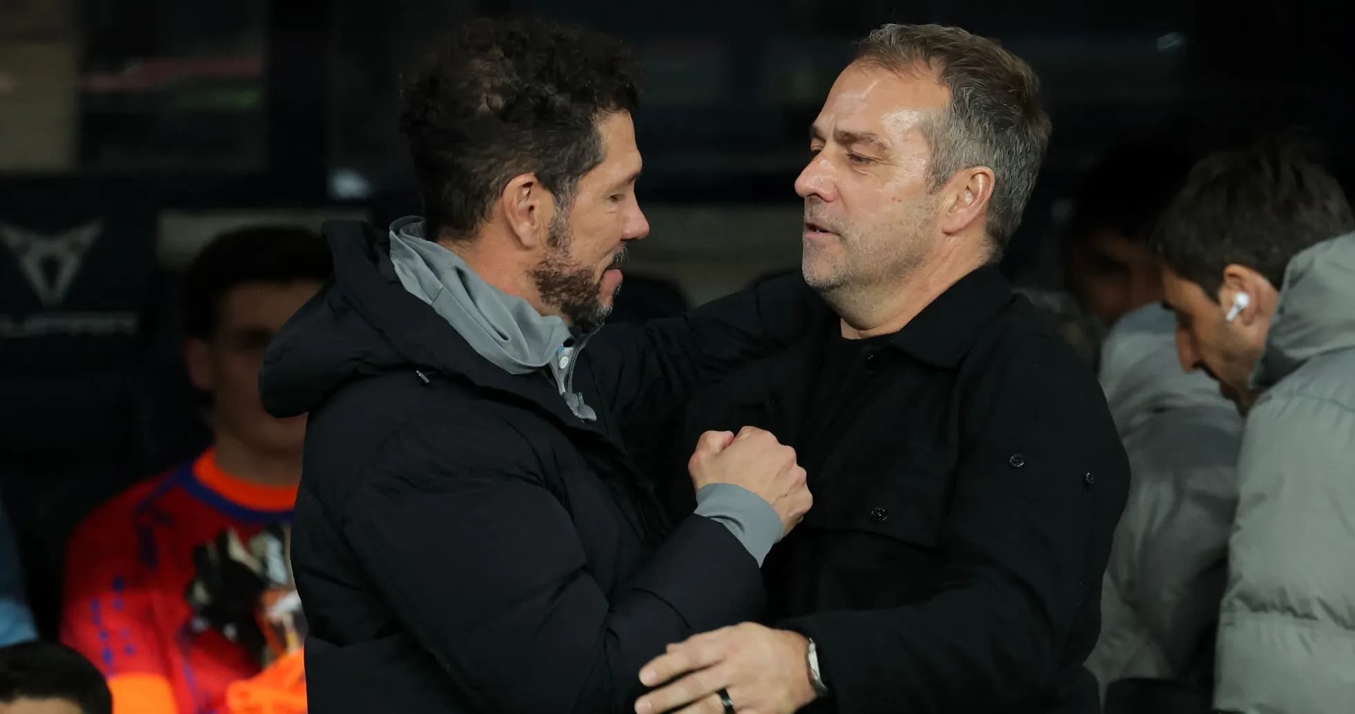 Entrenadores saludándose en el banquillo del estadio