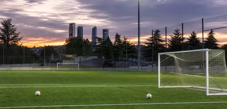 Campo de fútbol con pelotas y edificios al fondo
