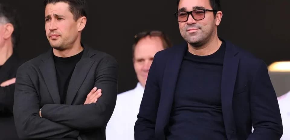 Dos hombres sentados en un palco durante evento deportivo