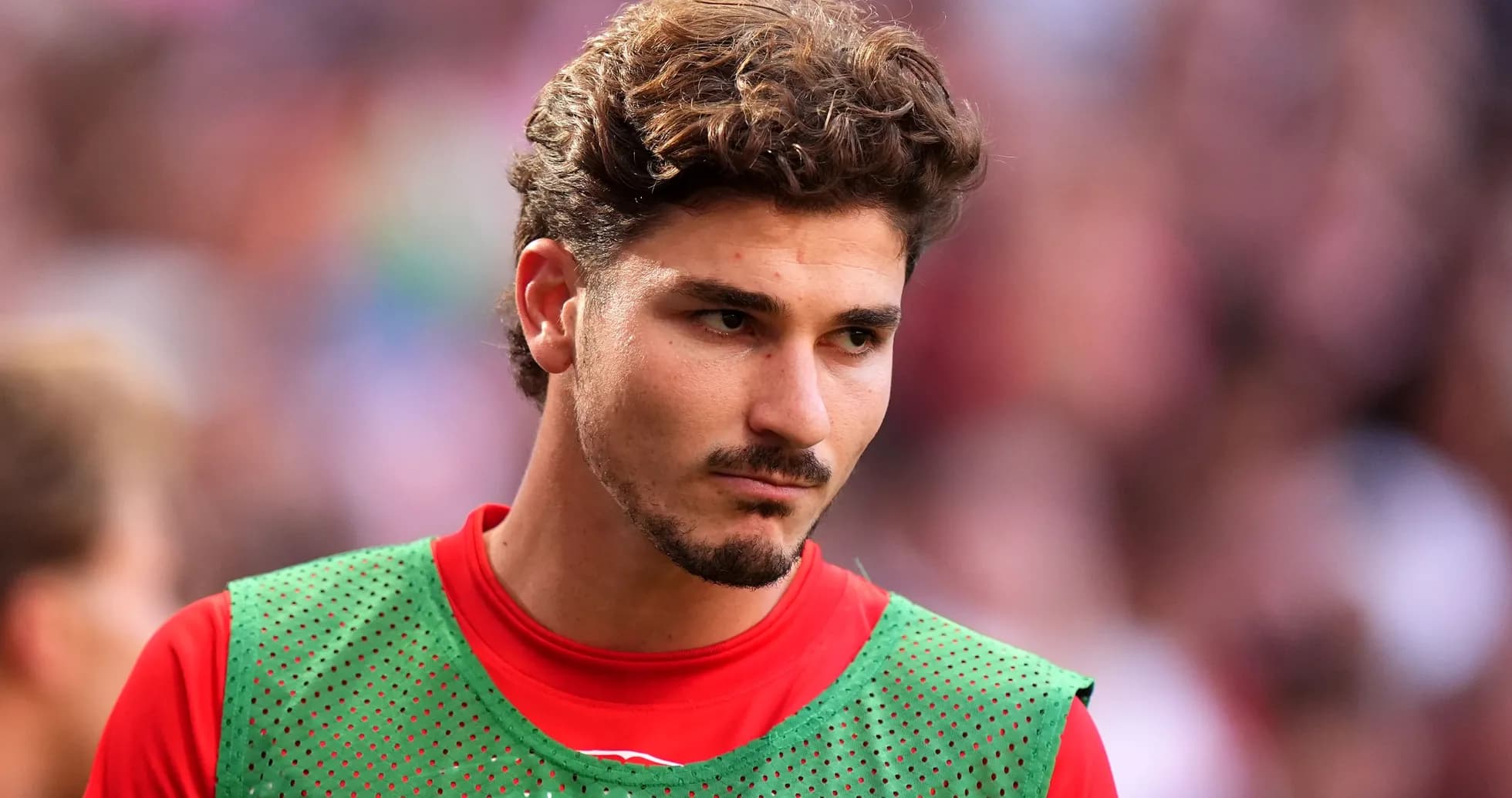 Jugador con camiseta roja y peto verde en el campo