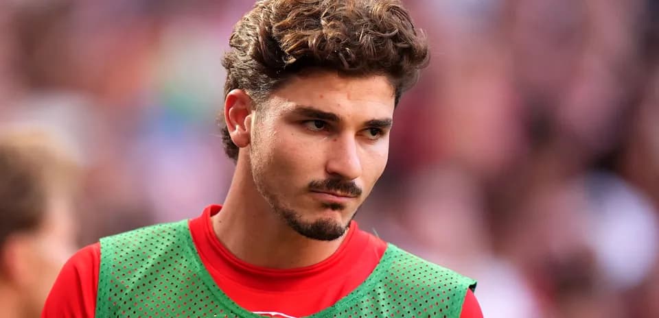 Jugador con camiseta roja y peto verde en el campo