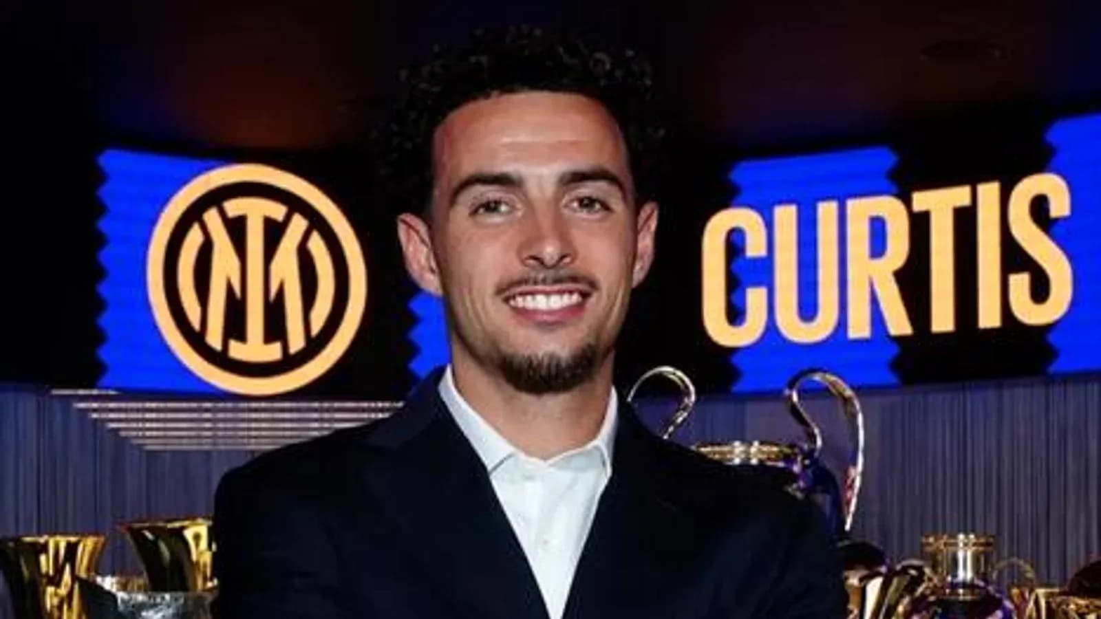 Jugador posando frente a trofeos y logo de Inter