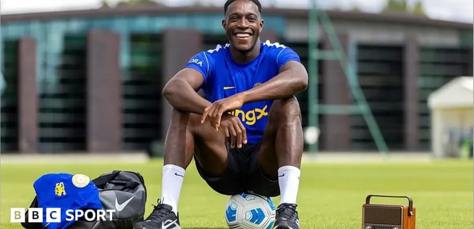 Jugador sentado en el campo con balón y mochila