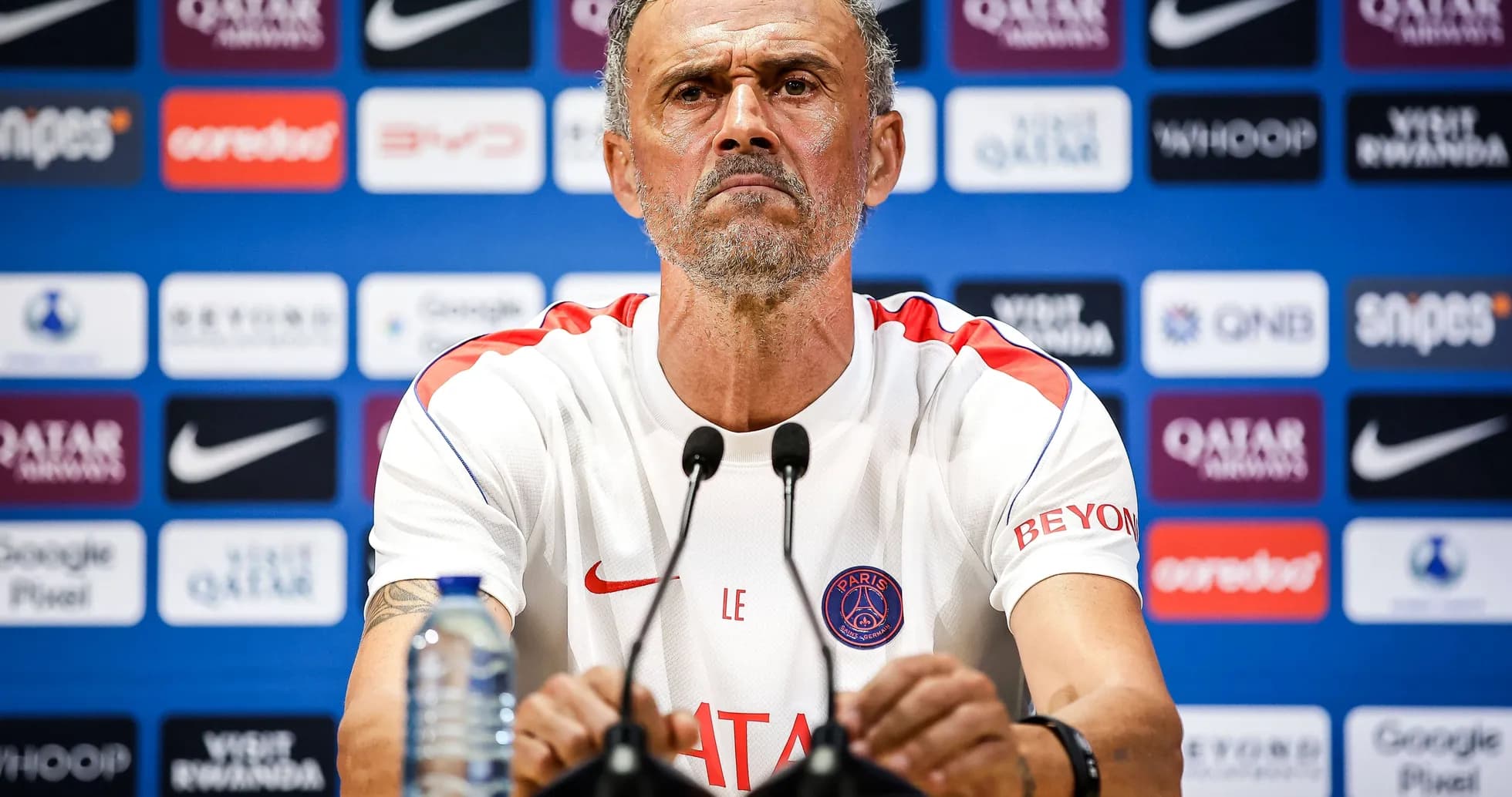 Entrenador en rueda de prensa con micrófonos frente