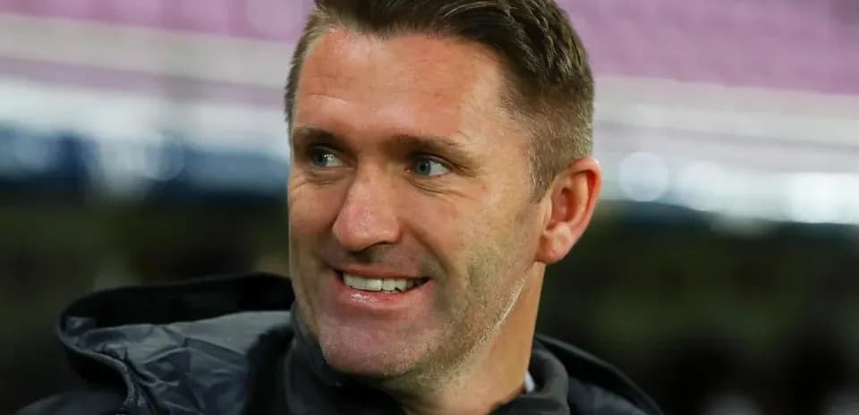 Entrenador sonriendo en el banquillo del estadio