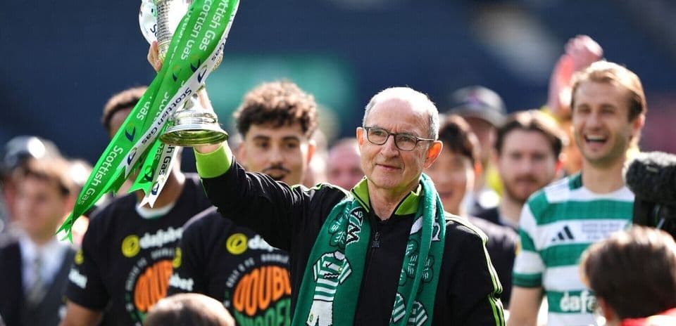 Entrenador levantando trofeo con jugadores detrás