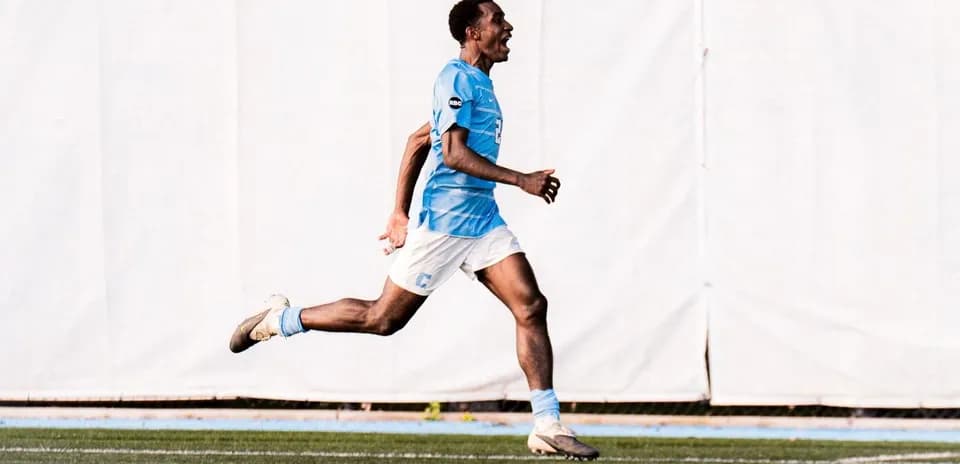 Jugador corriendo en el campo con camiseta azul