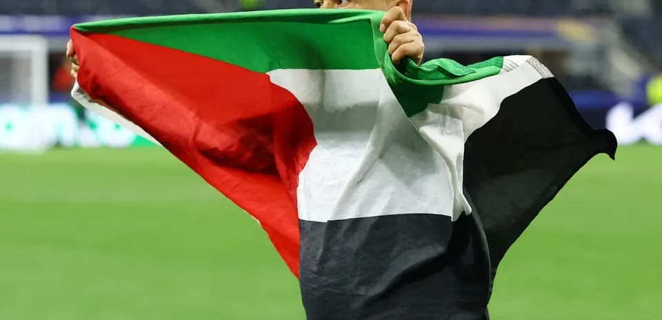 Hombre sosteniendo una bandera palestina en el campo
