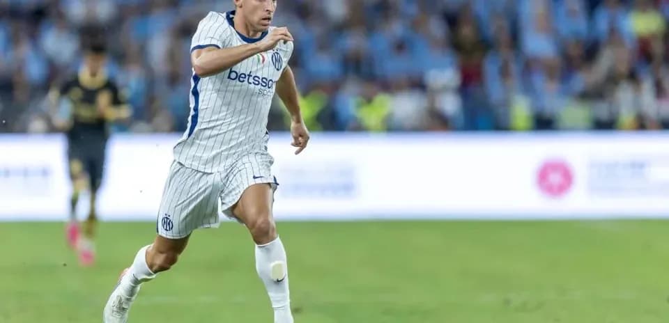 Jugador de fútbol corriendo con balón en el campo