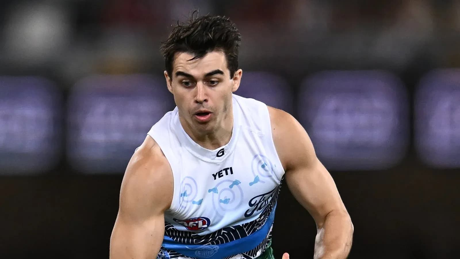 Jugador corriendo con balón durante un partido de AFL