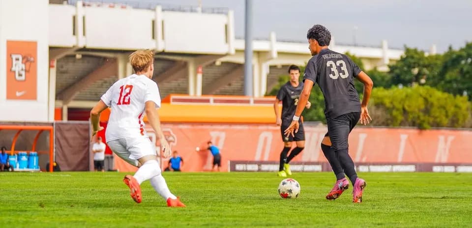 Jugador con balón frente a oponente durante partido de fútbol