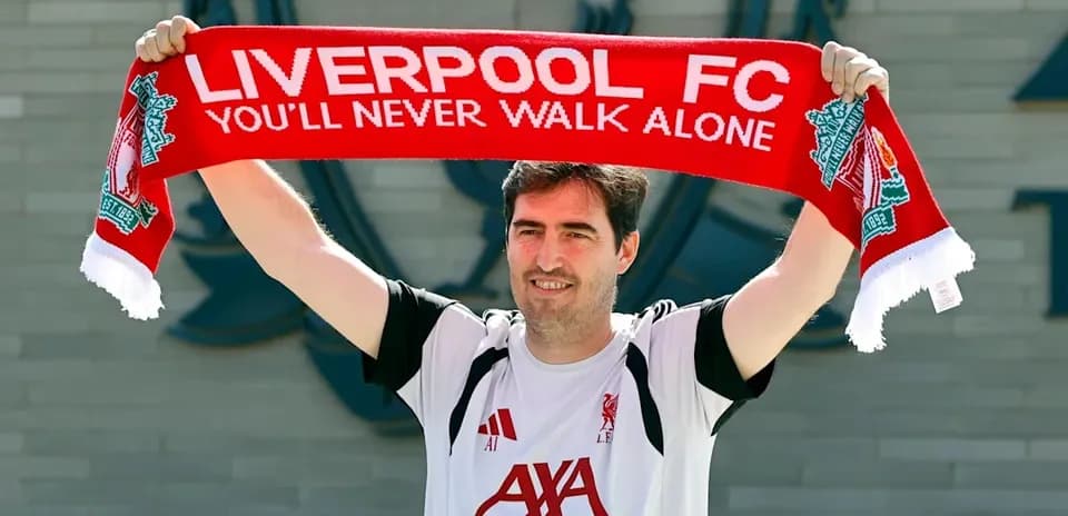 Jugador sosteniendo bufanda de Liverpool FC