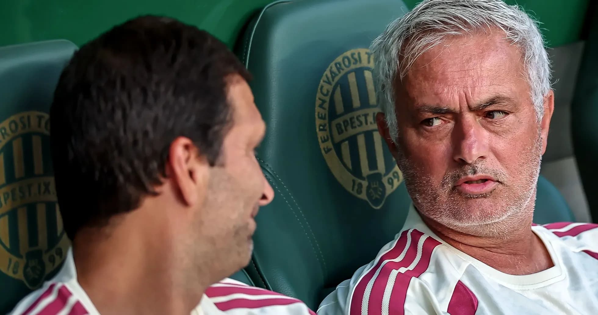 Entrenador conversando con jugador en banco de suplentes