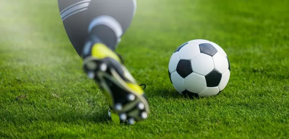 Jugador pateando un balón de fútbol en el césped