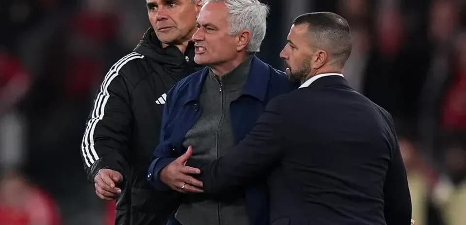 Entrenador siendo contenido por asistentes durante partido