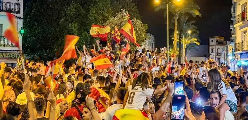 Celebration crowd waving Spanish flags at night