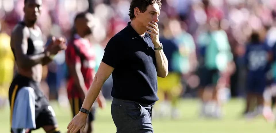 Entrenador caminando tras el partido con jugadores al fondo