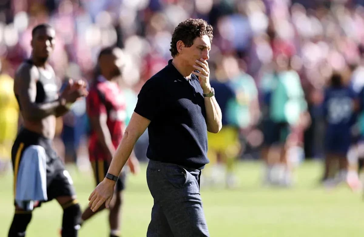 Entrenador caminando tras el partido con jugadores al fondo
