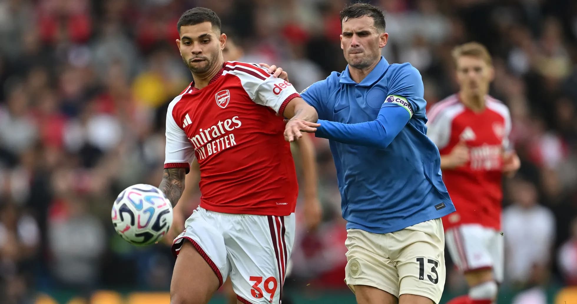 Jugador de Arsenal controlando el balón, rival persiguiéndolo