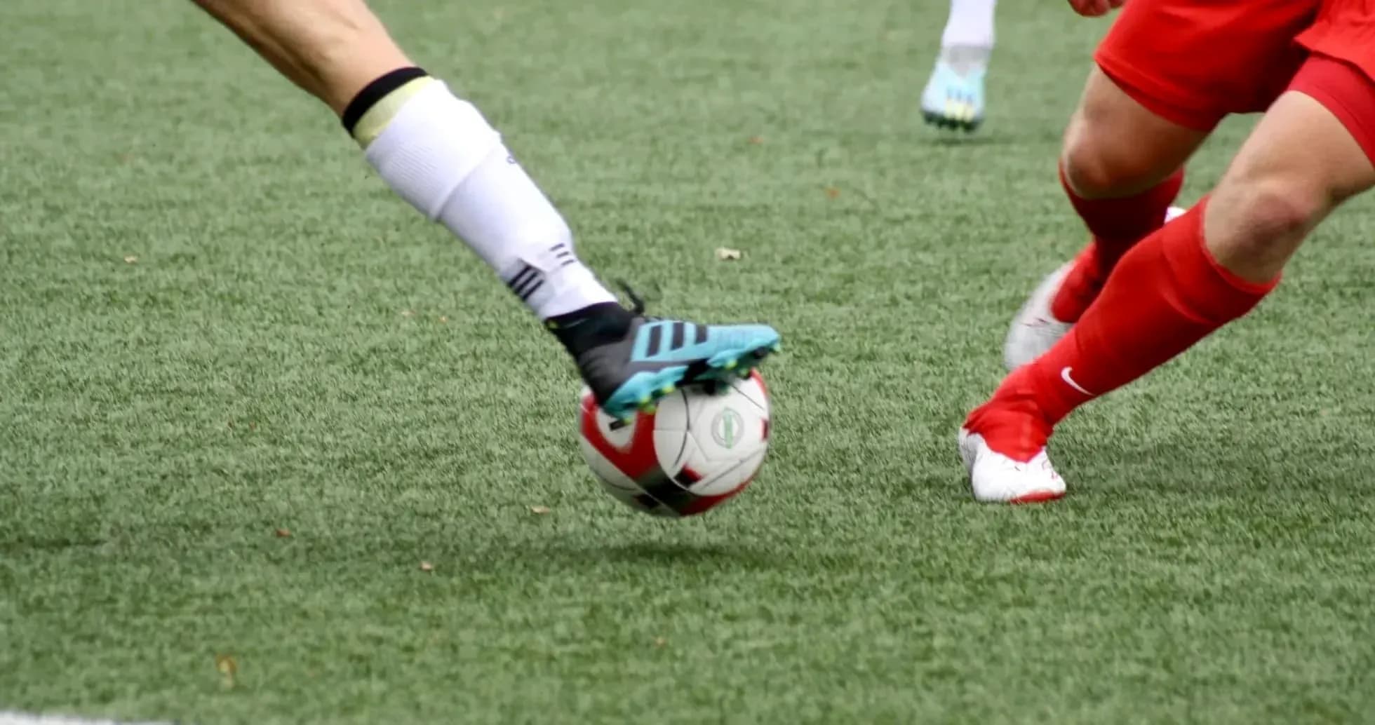 Jugadora de fútbol tocando el balón en el campo