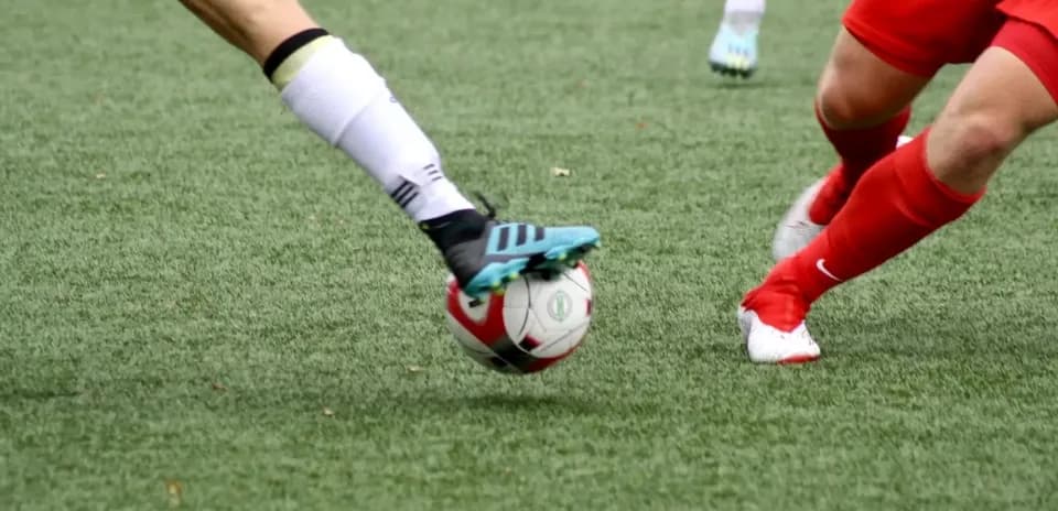 Jugadora de fútbol tocando el balón en el campo