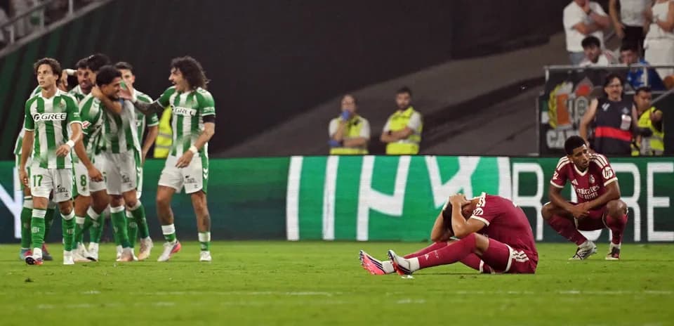 Jugadores de Betis celebrando, oponente en el suelo