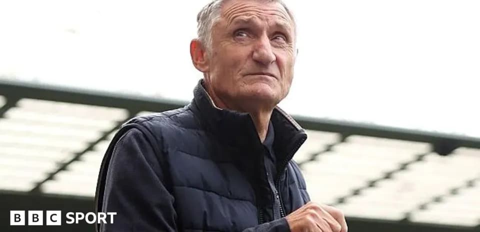 Hombre con chaqueta mirando hacia arriba en estadio