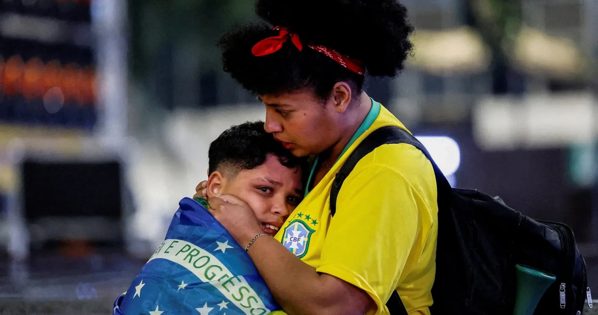 Madre abrazando a su hijo envuelto en bandera brasileña