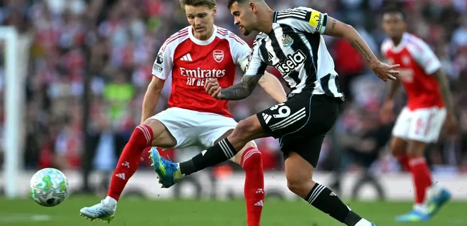 Jugador de Newcastle chutando el balón ante rival de Arsenal