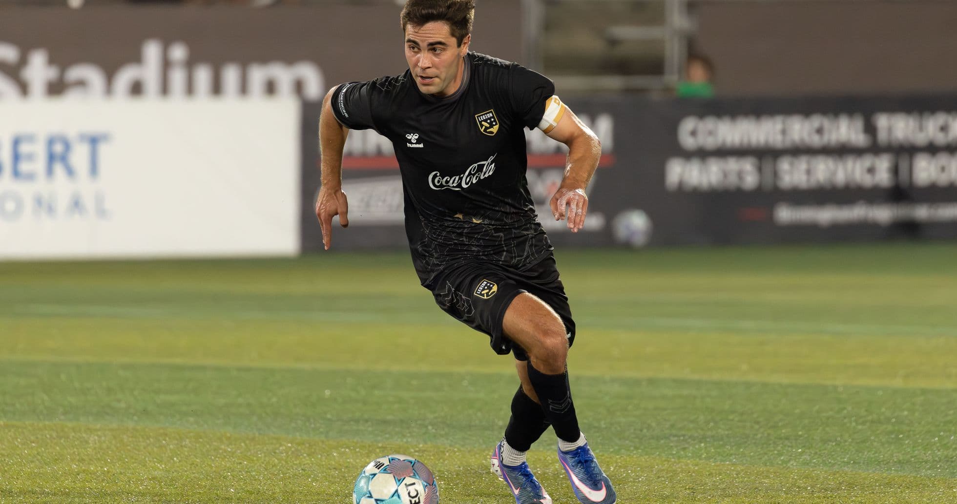 Jugador corriendo con el balón en el estadio