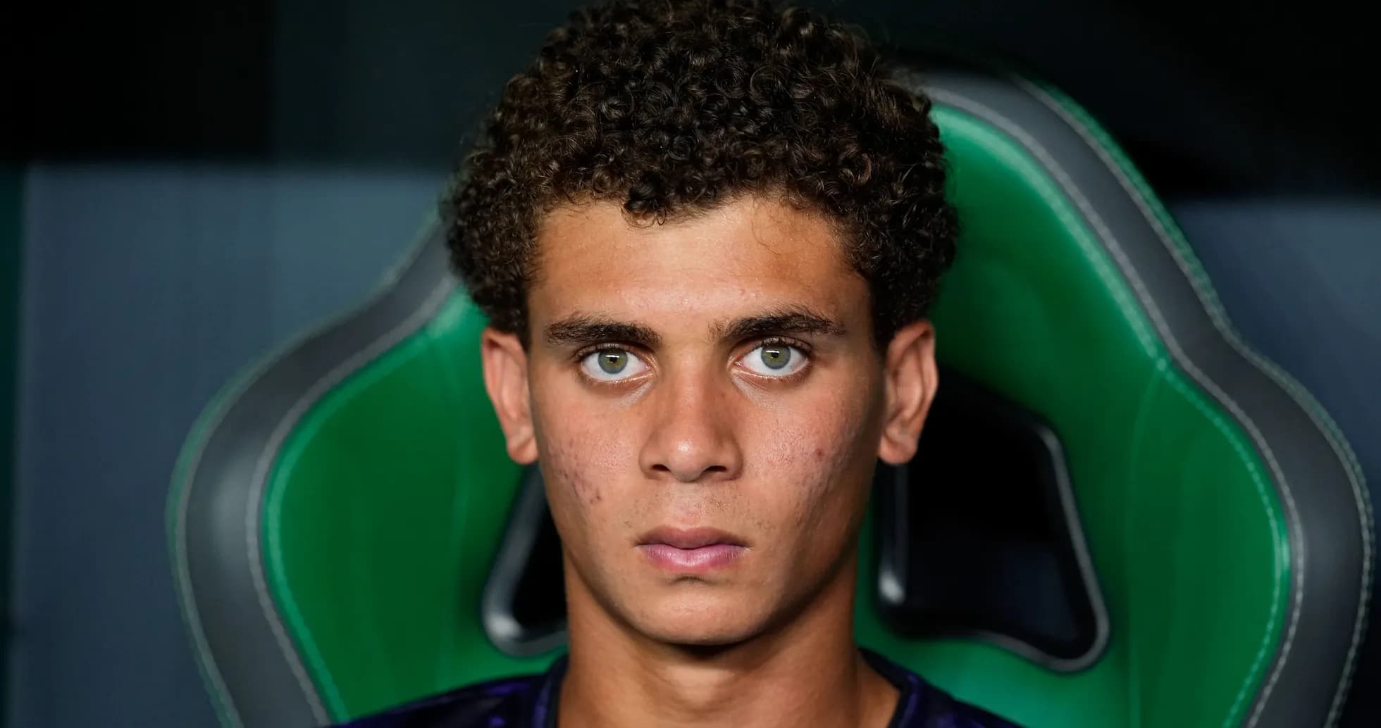 Jugador sentado en silla de equipo, mirada seria