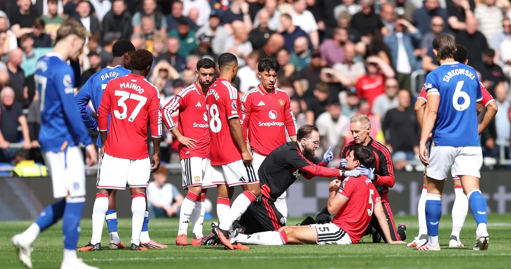 Jugadores de Manchester United rodeando a compañero lesionado