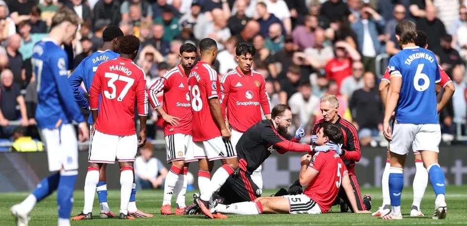 Jugadores de Manchester United rodeando a compañero lesionado