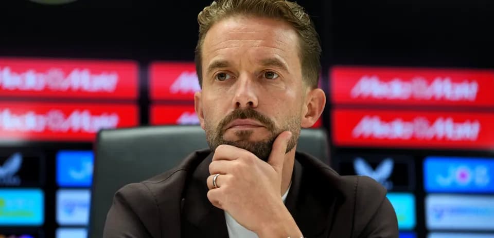 Entrenador en conferencia de prensa con fondo de logos