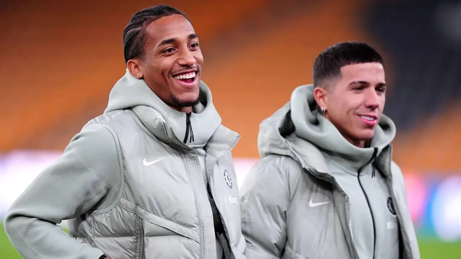 Dos jugadores sonriendo durante calentamiento en el campo