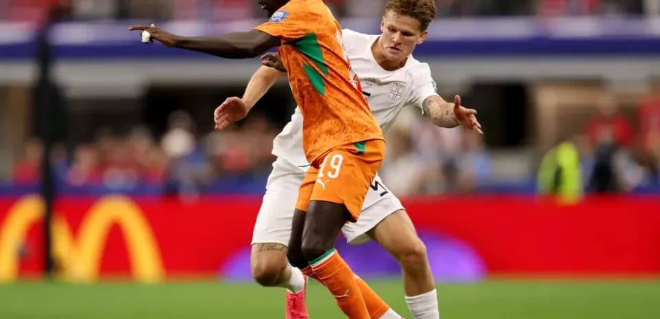 Jugador con camiseta naranja driblando a oponente en campo