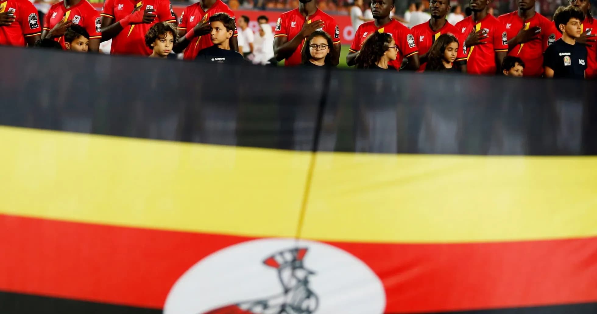 Jugadores de Uganda cantando himno frente a bandera