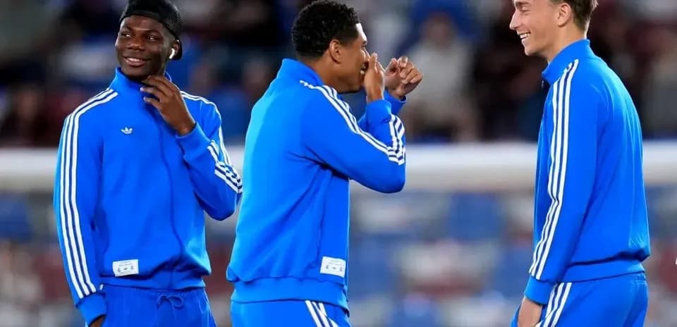 Tres jugadores en ropa de entrenamiento sonriendo juntos