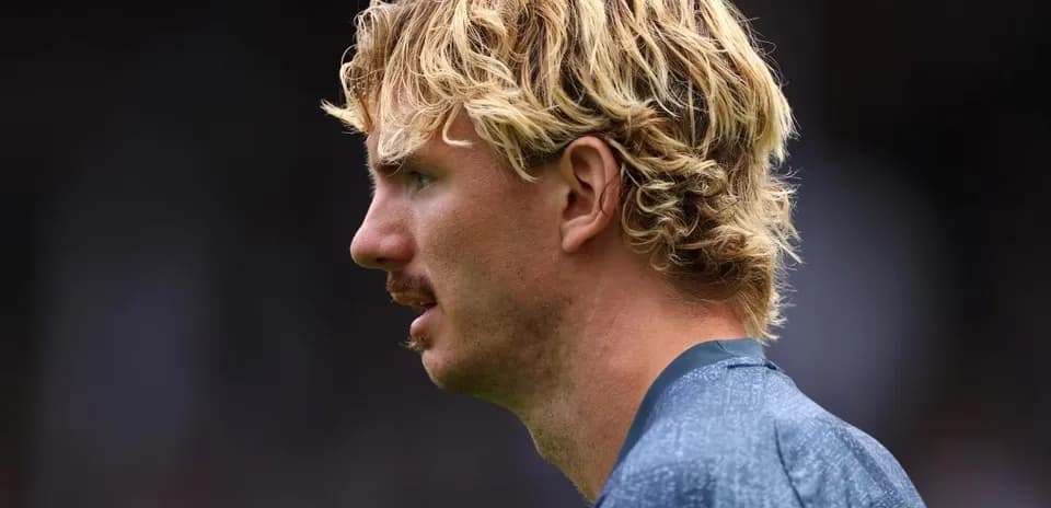 Jugador con cabello rizado y bigote en perfil