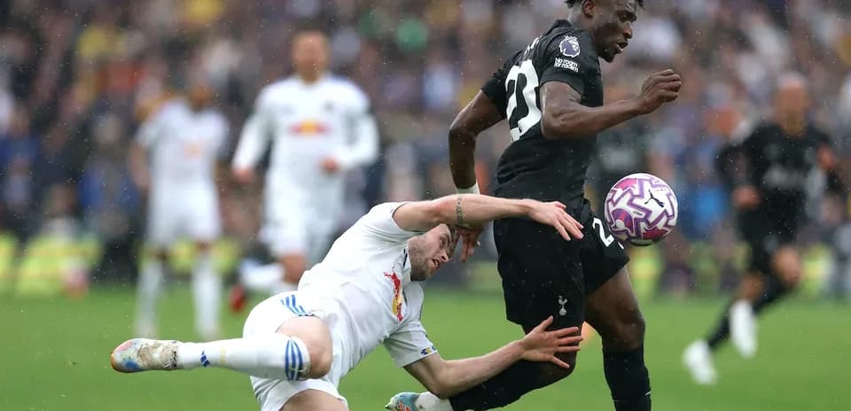 Jugador de Tottenham driblando mientras es tackleado