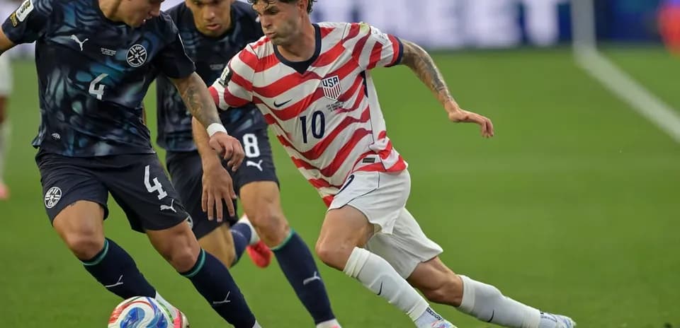 Christian Pulisic dribbling past Paraguayan defenders