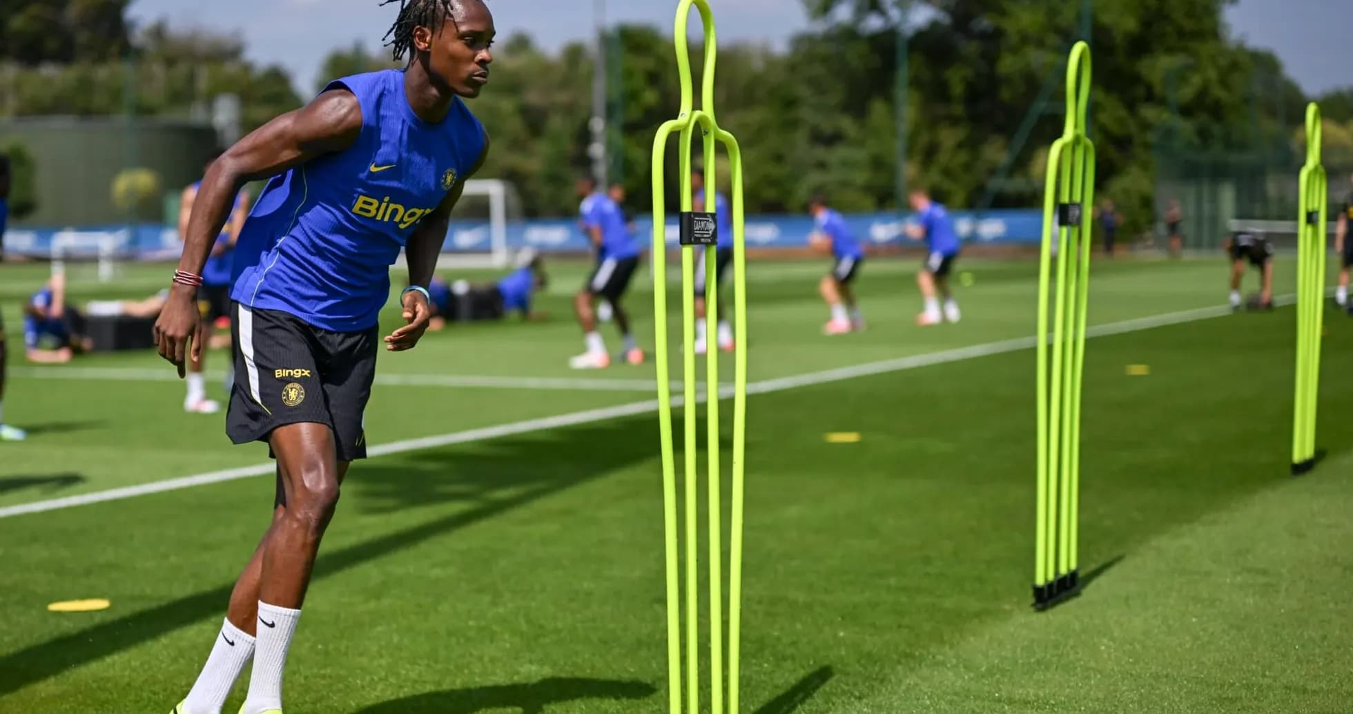 Jugador entrenando con conos en campo de entrenamiento
