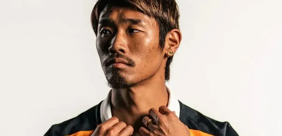 Jugador posando con camiseta deportiva en fondo neutro