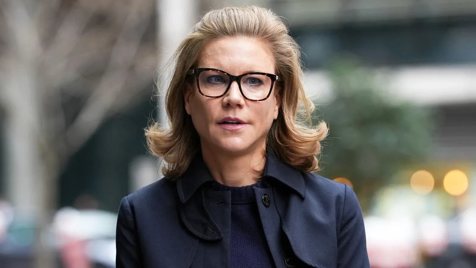 Mujer con gafas y abrigo caminando por la calle
