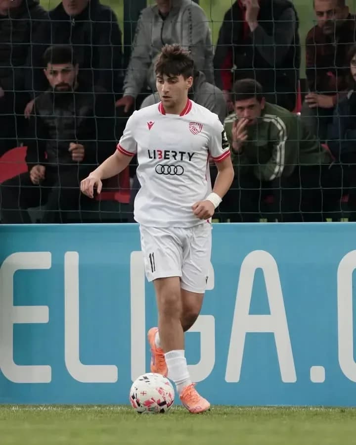 Jugador con balón en campo de fútbol durante partido