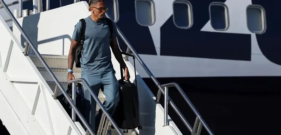 Jugador bajando de avión con maleta en mano