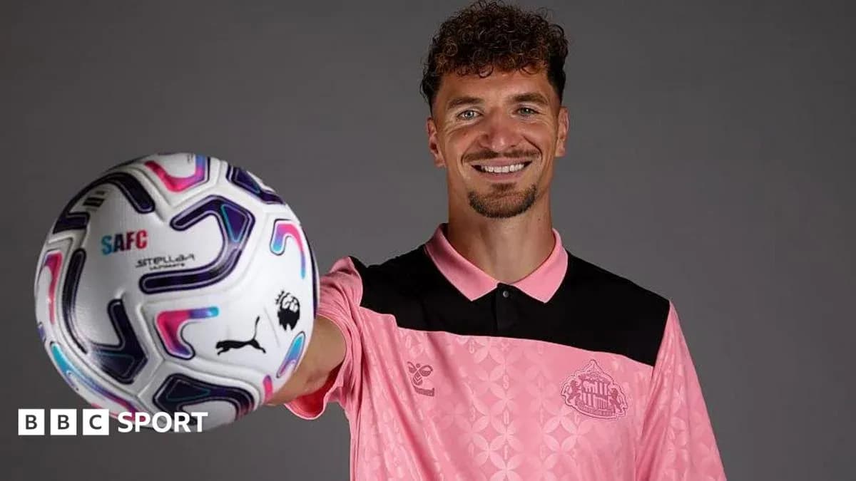 Jugador sosteniendo un balón de fútbol en estudio