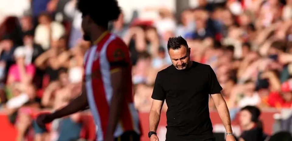 Entrenador caminando con expresión seria durante partido