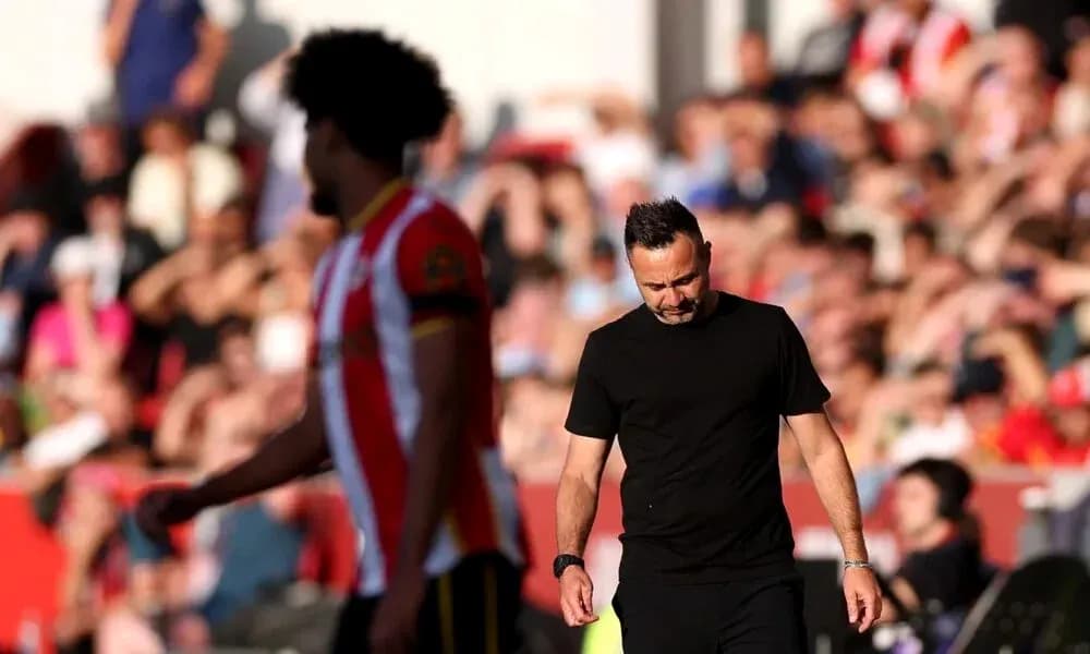Entrenador caminando con expresión seria durante partido