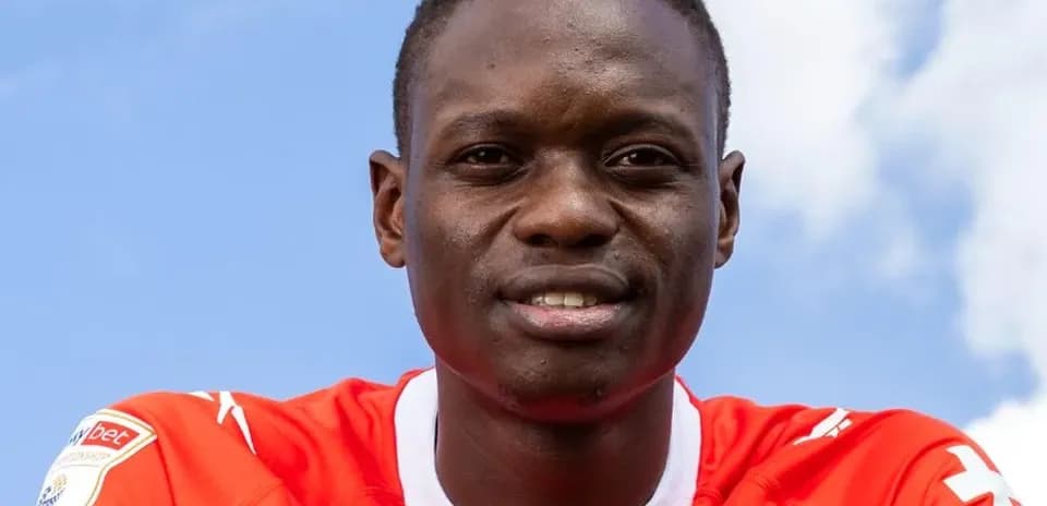 Jugador sonriendo con camiseta roja bajo cielo azul